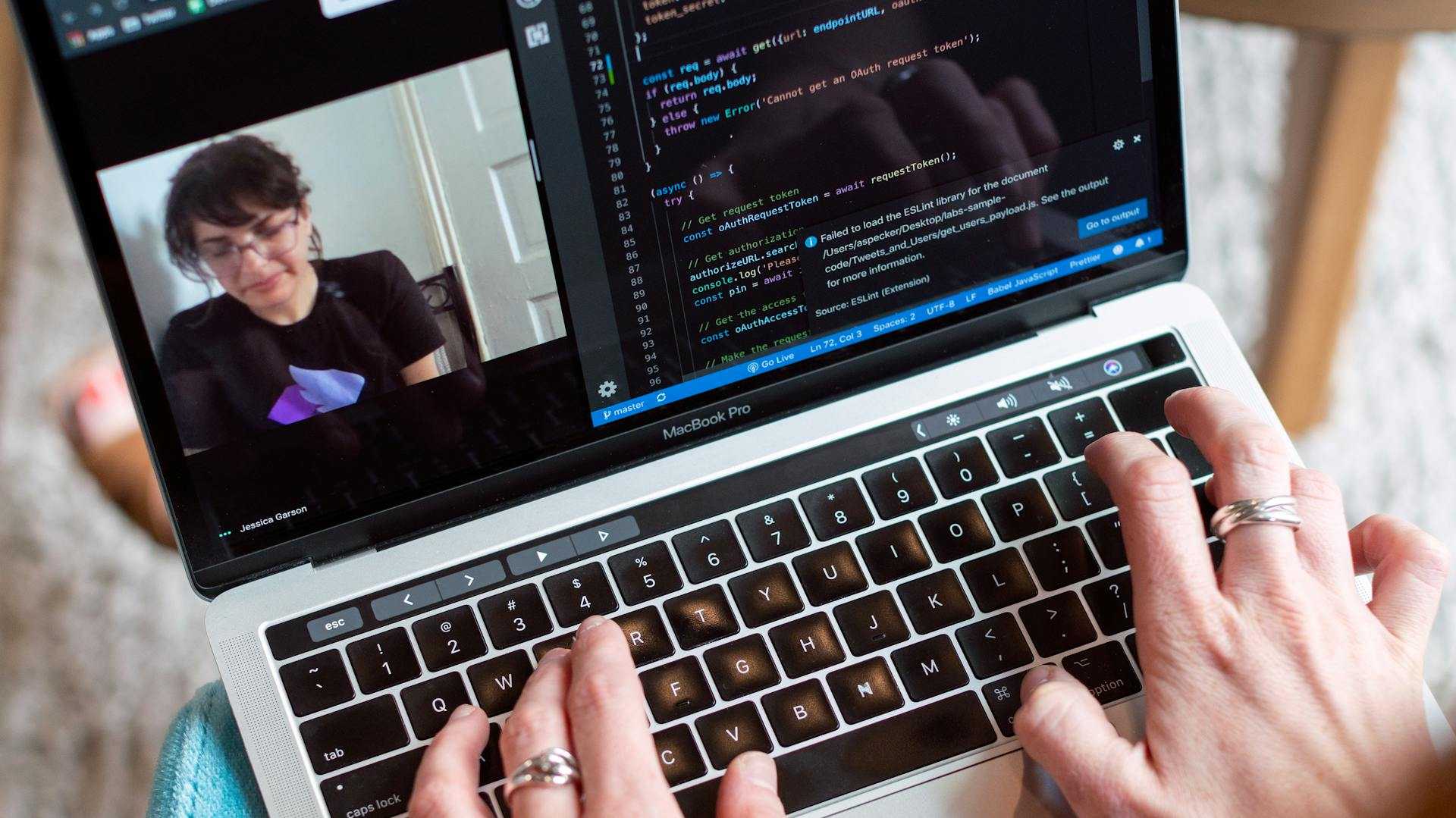 Someone using a MacBook to code while video calling a colleague.