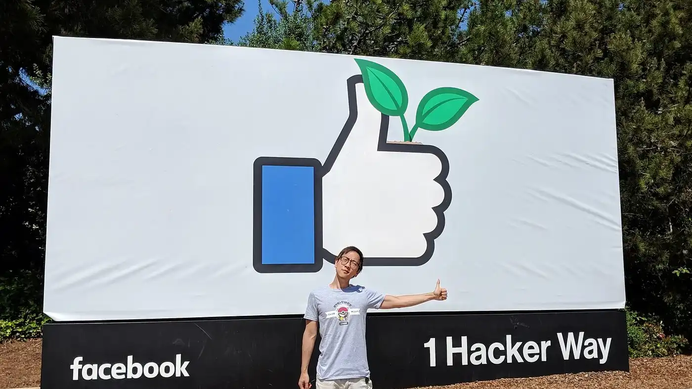 Henry Chong making a thumbs up gesture in front of the famous Facebook sign on the main campus of Meta HQ.
