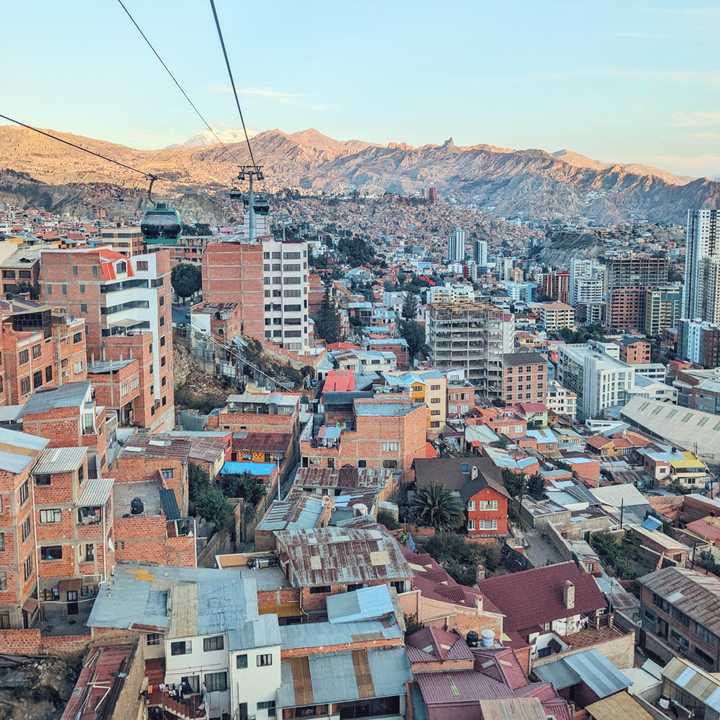 Cable car over a colourful city in a caldera with mountains in the background